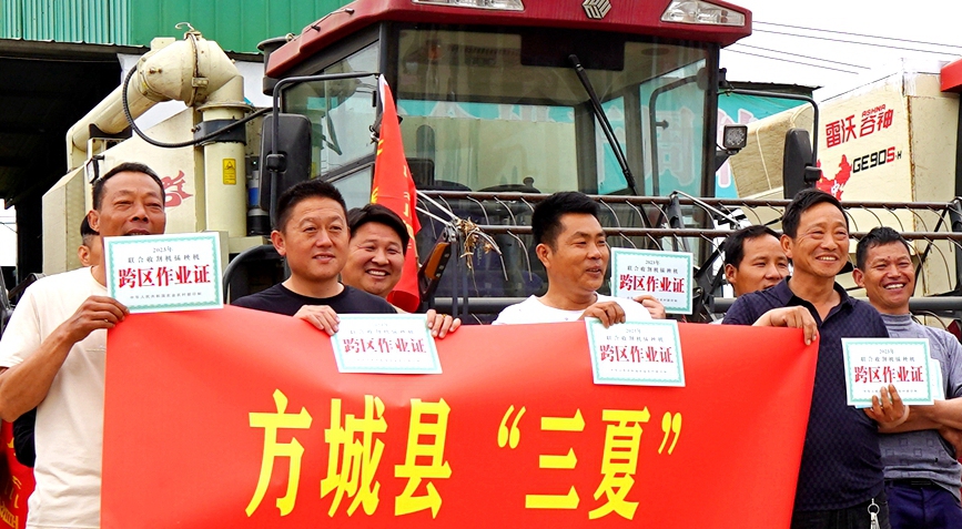 河南省方城县农机中心工作人员在农机合作社现场给小麦联合收割机机手发放跨区作业证。李超峰摄