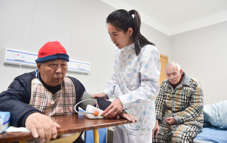 河南洛阳市涧西区重庆路街道三社区养老服务中心，工作人员为享受托养服务的老人们进行健康监测。黄政伟摄