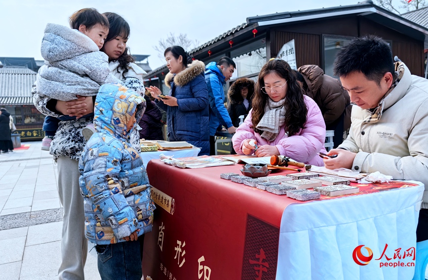 市民在观看肖形印的制作。人民网侯琳琳摄