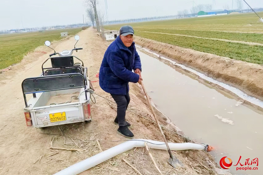 河南省封丘县鲁岗镇康寨村村民石秀业在田间浇麦子。人民网 程明辉摄