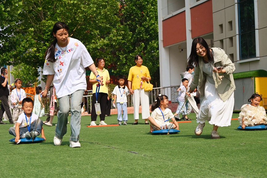 5月28日，河南省南阳市社旗县第三幼儿园举办“双节同庆 童心‘粽’在”亲自游园活动，家长和孩子们在玩同舟共济游戏。申鸿皓摄