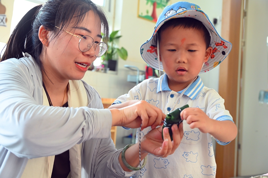 5月28日，河南省南阳市社旗县第三幼儿园举办“双节同庆 童心‘粽’在”亲自游园活动，家长和孩子一起包粽子。申鸿皓摄