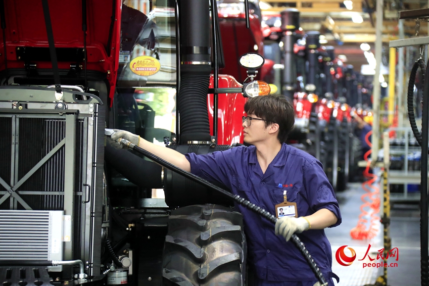 技术人员对即将下线的拖拉机加注油液。人民网记者慎志远摄