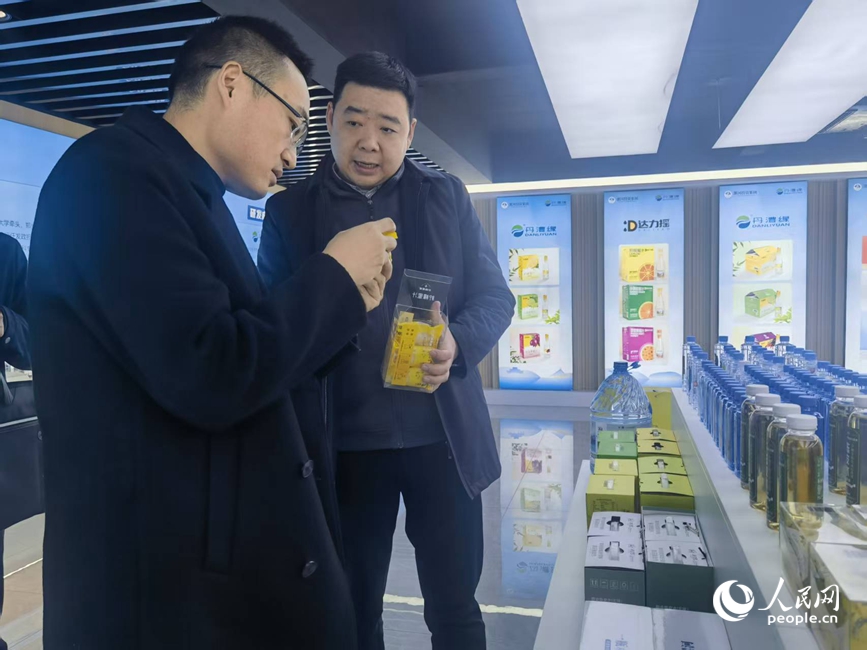 李哲（左）向人民网记者介绍公司产品。人民网记者 尚明桢摄