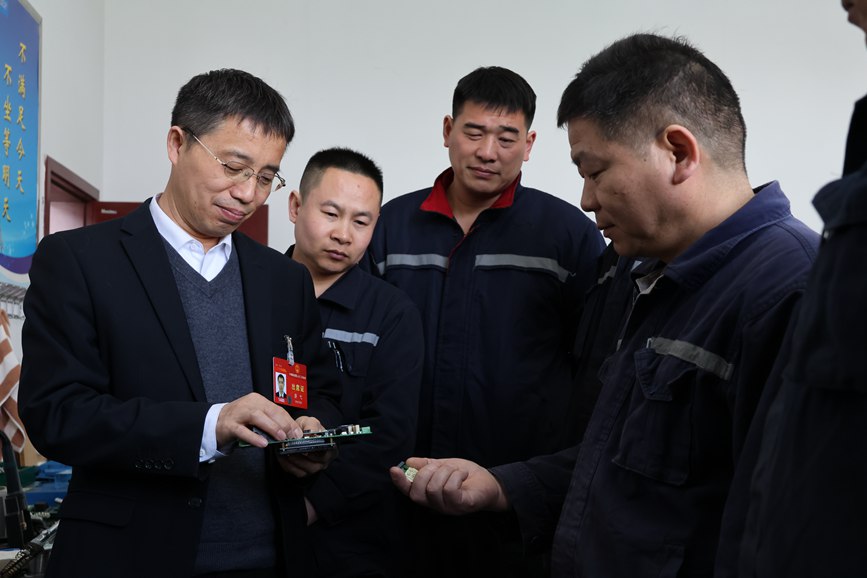 游弋（左一）正在耐心帮助职工解决技术难题。王宇航摄