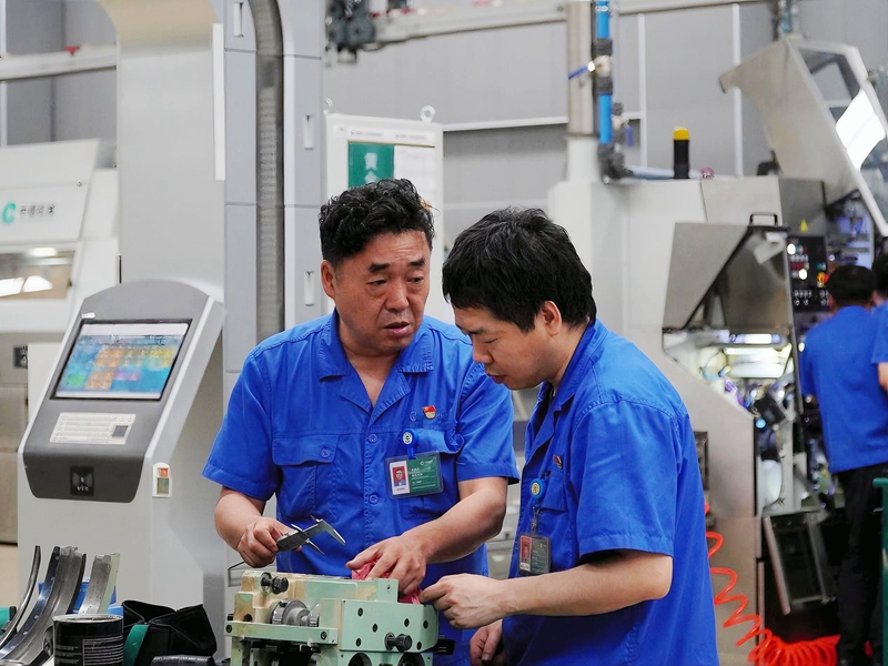 洛阳卷烟厂卷包车间电工乔晋伟与维修工讨论设备拆解问题。邓中元摄