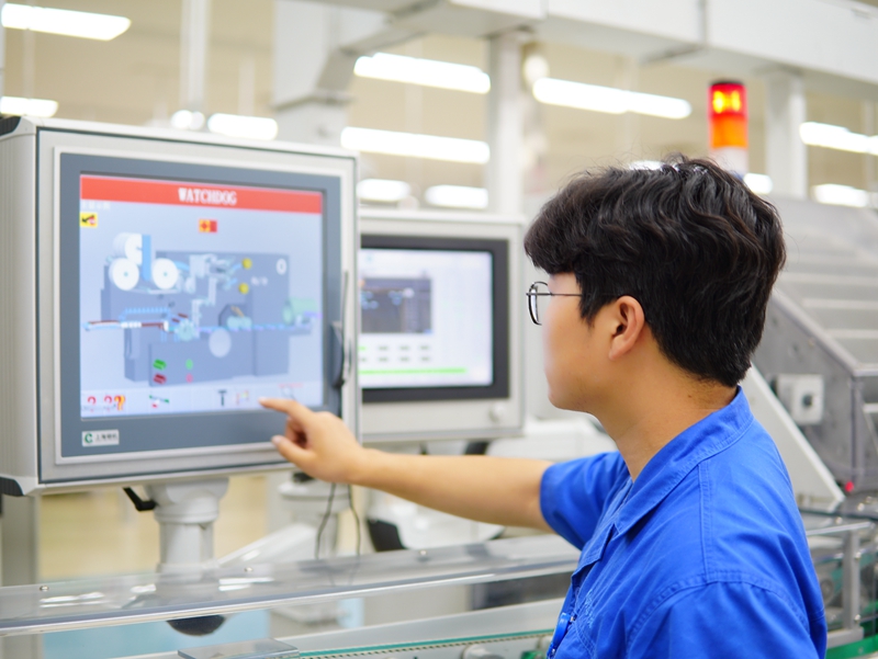 洛阳卷烟厂卷包车间青年操作工在设备屏幕上调整参数。邓中元摄