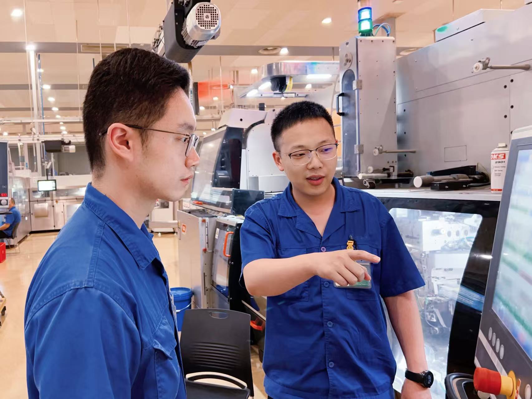 卷包车间带班长和操作工交流设备操作要点。杨天语摄