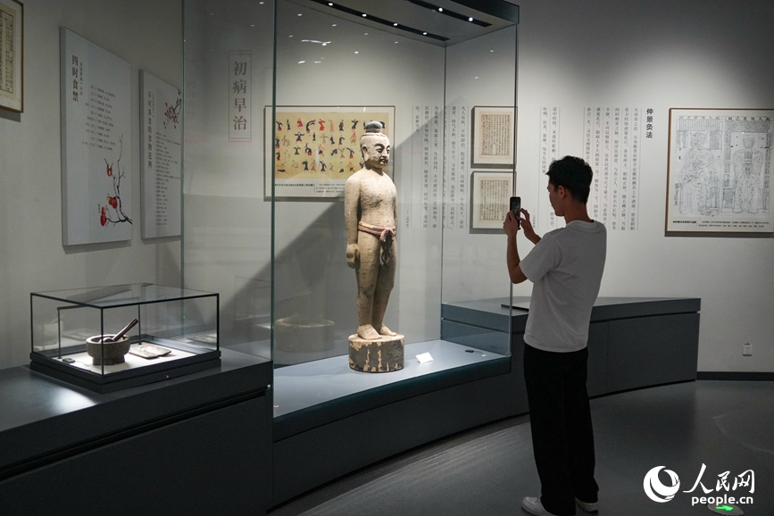 南阳医圣祠的展厅内，观众正在拍摄展出的古代中医针灸人像展品。实习生杨彬摄