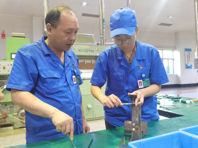 图为曲军建指导青年职工张艺方测量导向装置支承螺栓