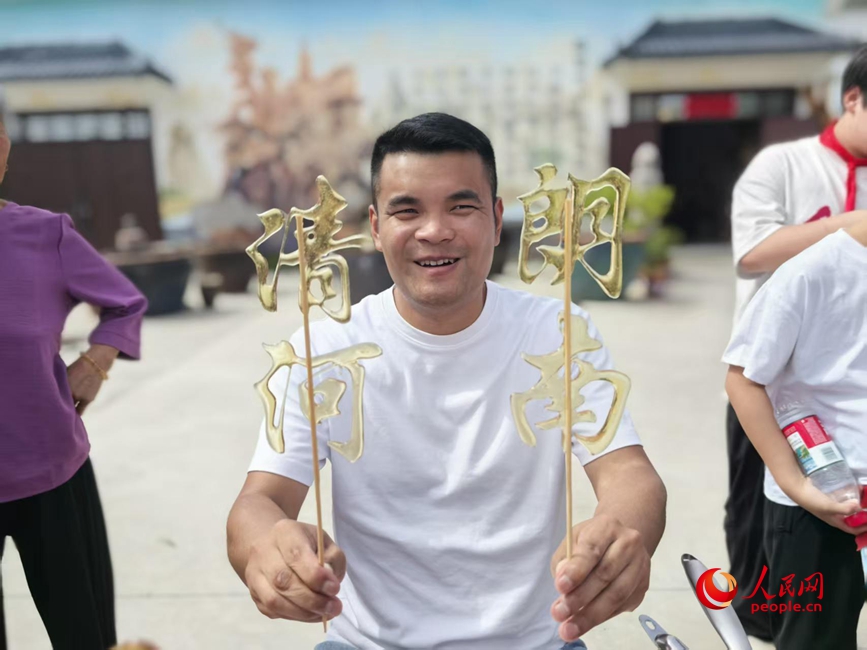 乡村大集上，摊主用麦芽糖做了“清朗河南”的糖画。人民网记者 王佩摄