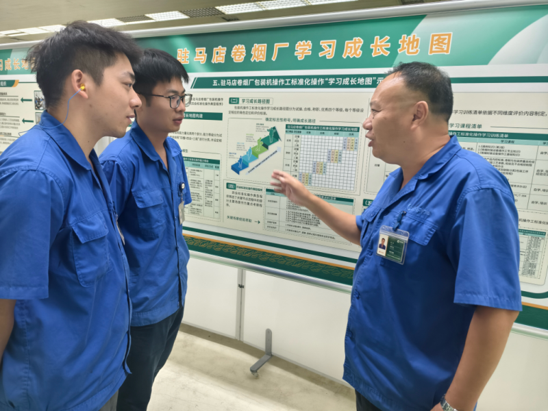 班长戚勇（右一）向新进员工介绍“学习成长地图”  。张艳摄